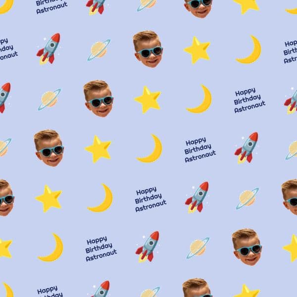 Periwinkle blue birthday wrapping paper with rockets, ringed planets, stars and a personalised astronaut name badge
