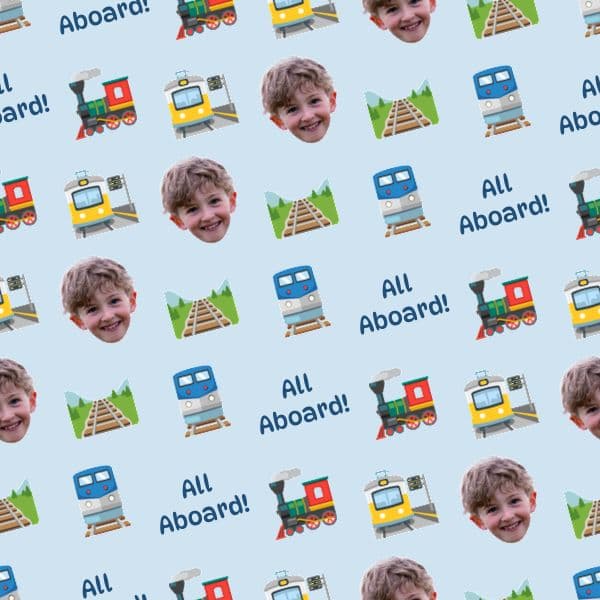 Wrapping paper with cartoon steam trains, stations and tracks in red, blue and yellow, with a child's photo and station name