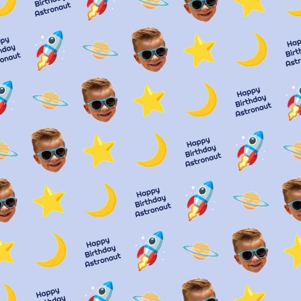 Periwinkle blue birthday wrapping paper with rockets, ringed planets, stars and a personalised astronaut name badge